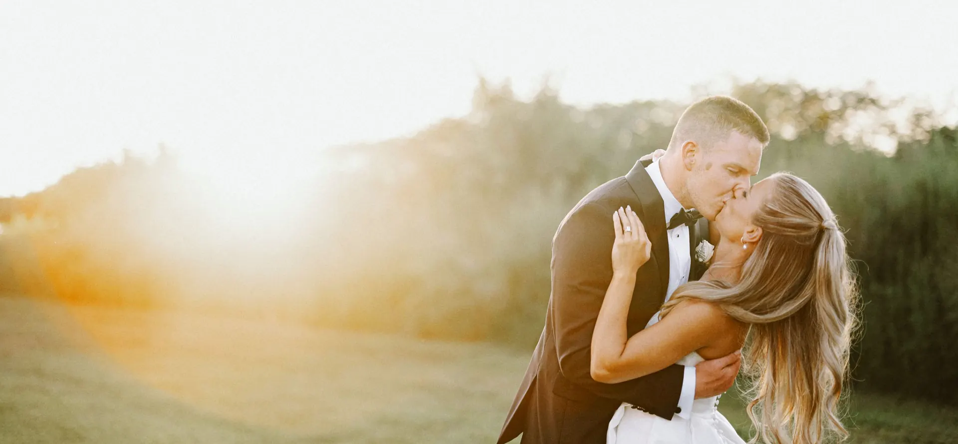 Groom dipping the bride for a kiss in warm sunset light at Bishop Farmstead in Shamong, New Jersey