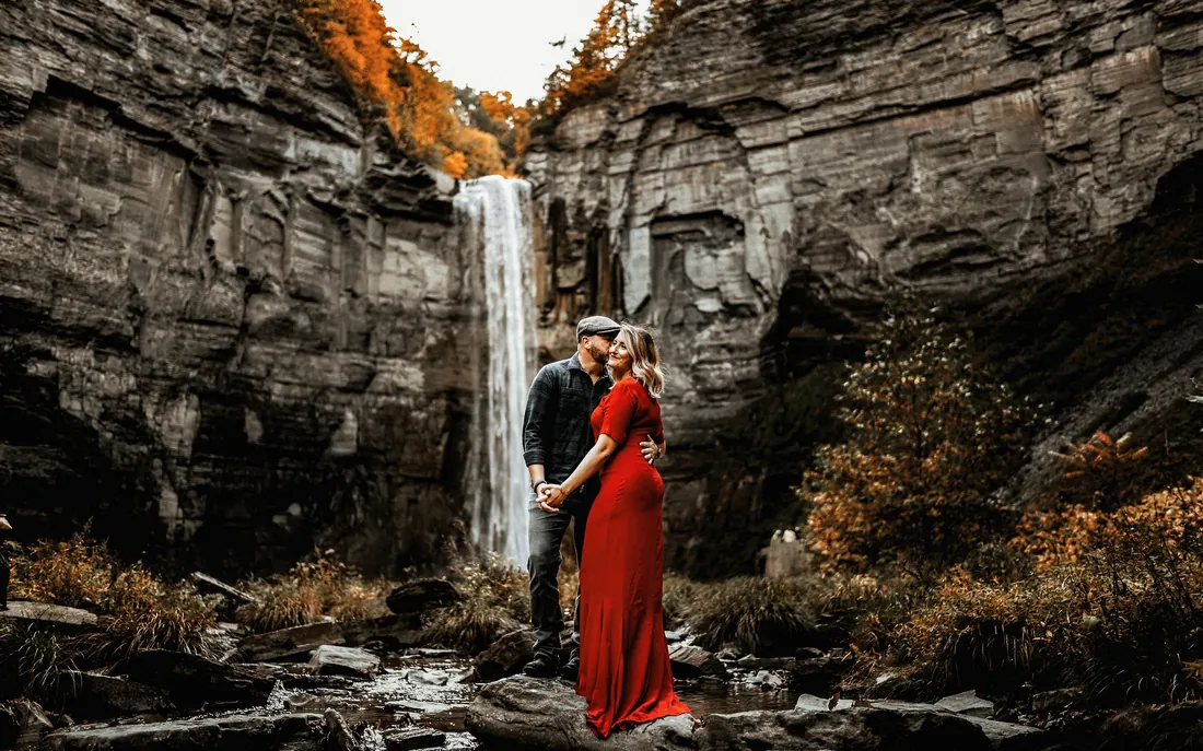 Engaged couple kissing in front of a waterfall in a rocky gorge