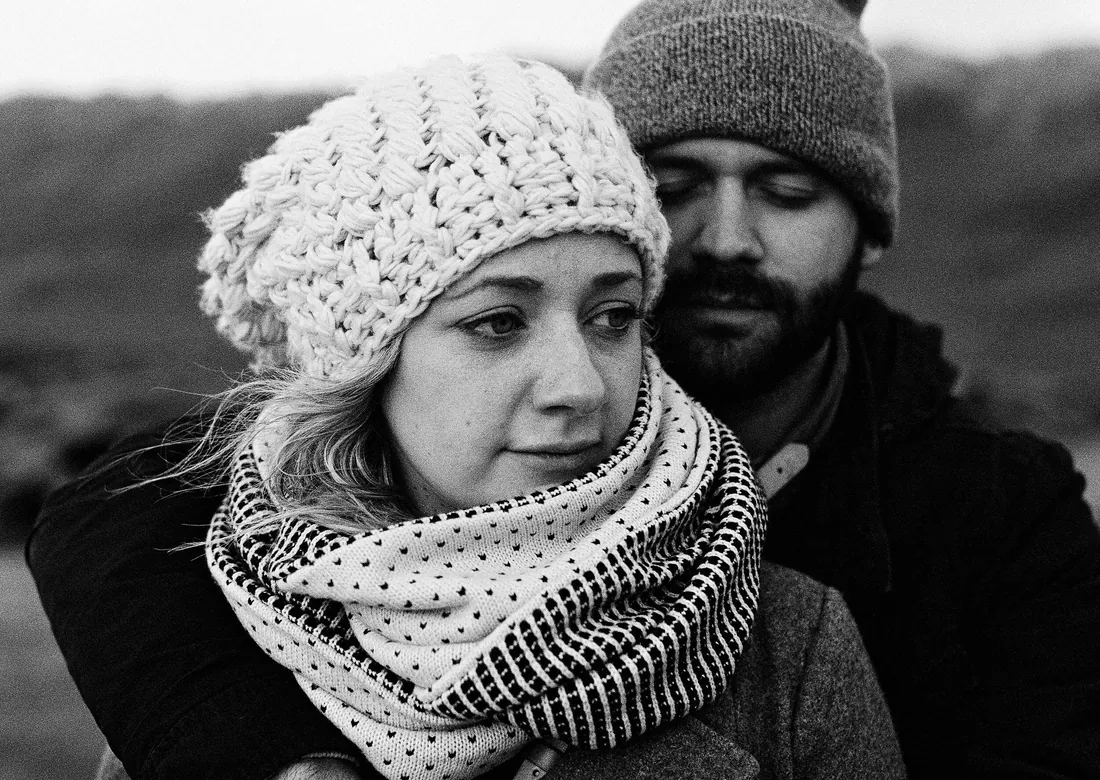 Black and white film photograph of a couple bundled up in winter hats and scarves