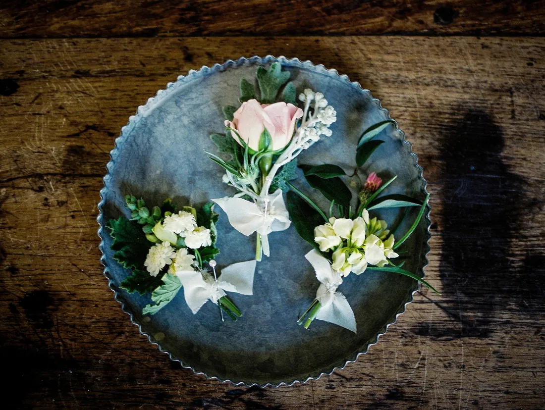 Film photograph of boutonnieres on a metal tray on a rustic table