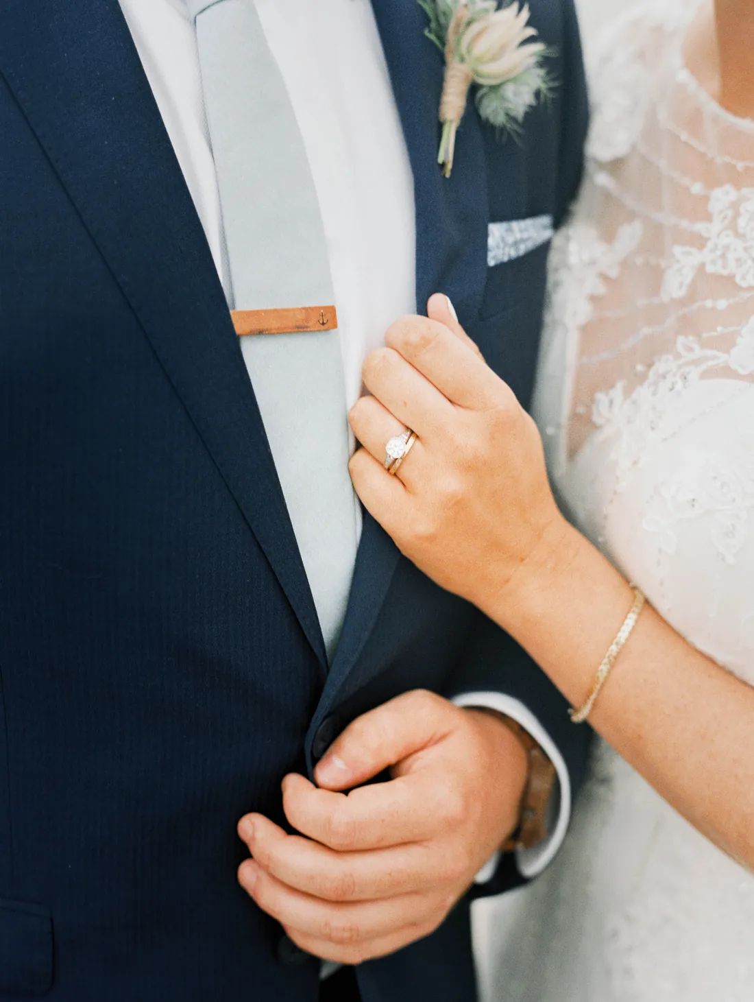 Film close-up of a bride's hand and engagement ring on the groom's lapel