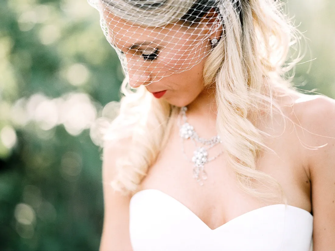 Film portrait of a bride looking down in a birdcage veil