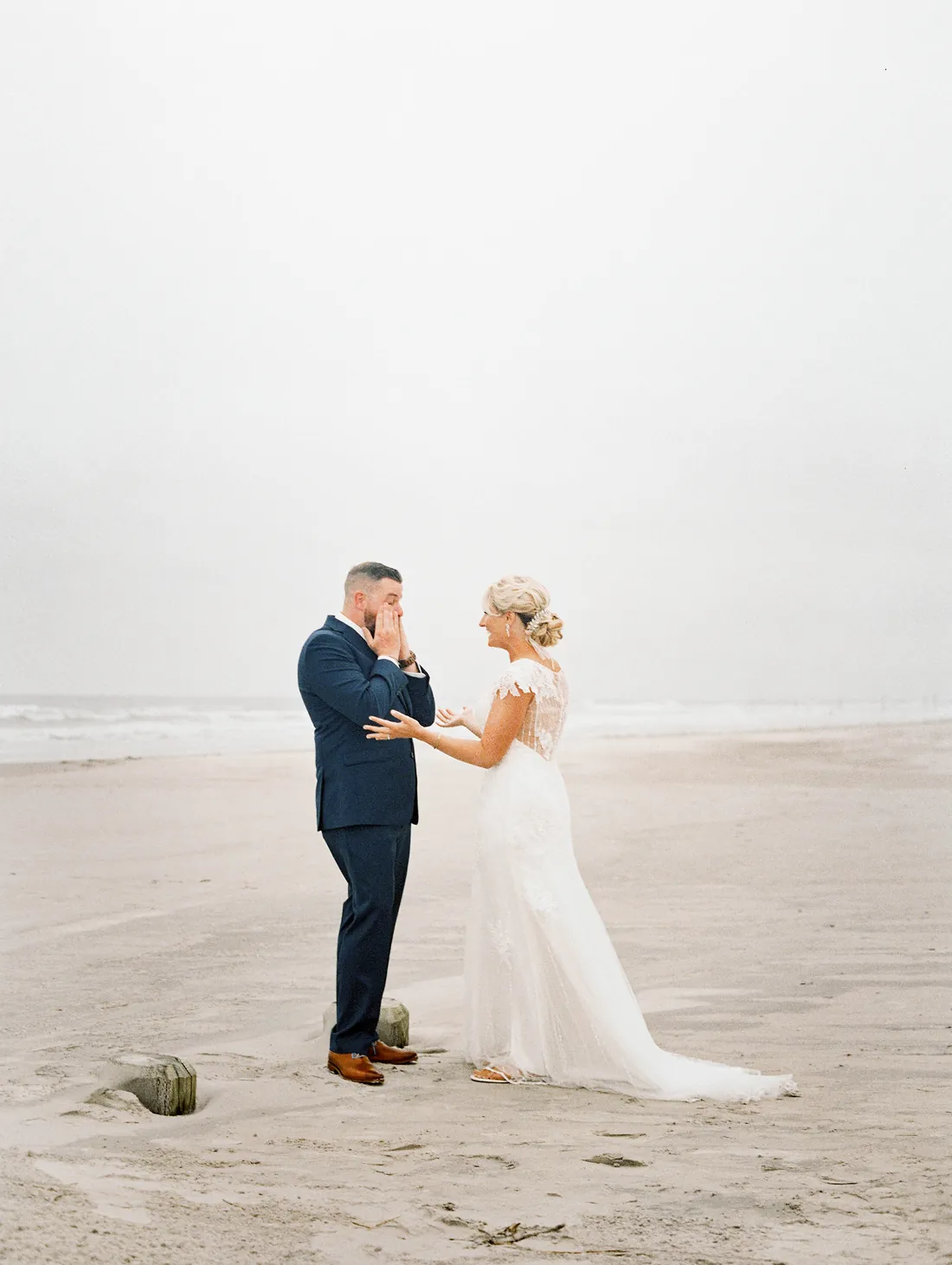 Film photograph of an emotional first look on a foggy beach