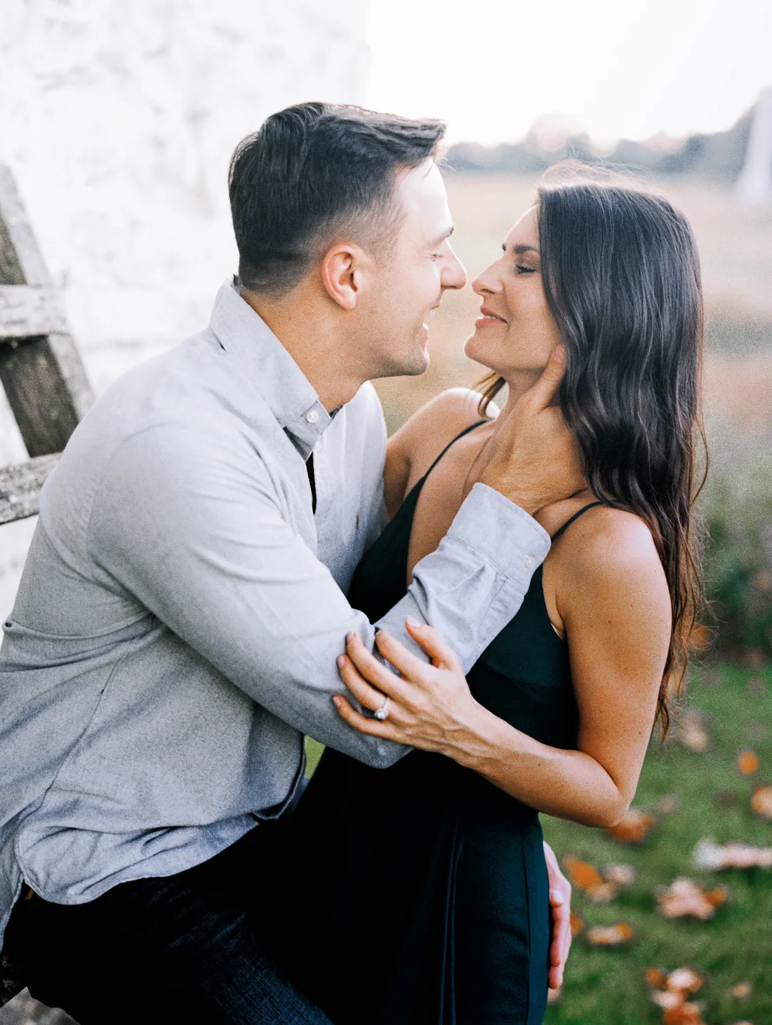 Film photograph of an engaged couple leaning in for a kiss outdoors