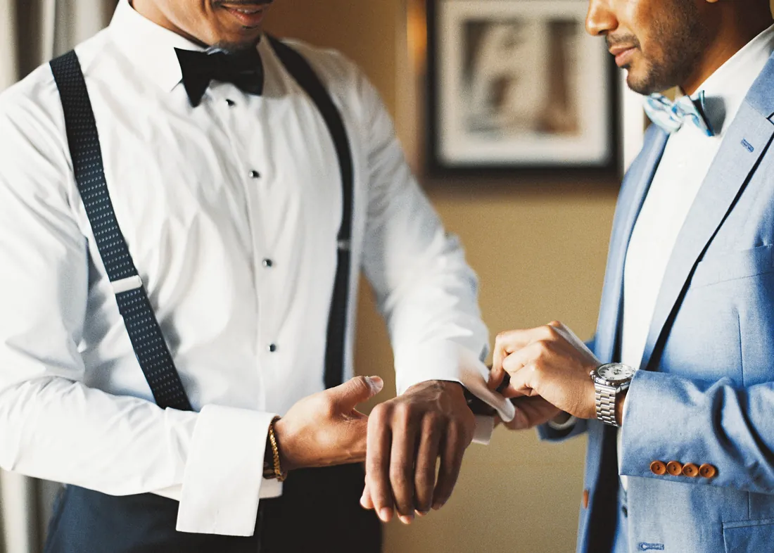 Film photograph of a groomsman helping the groom with his cufflinks