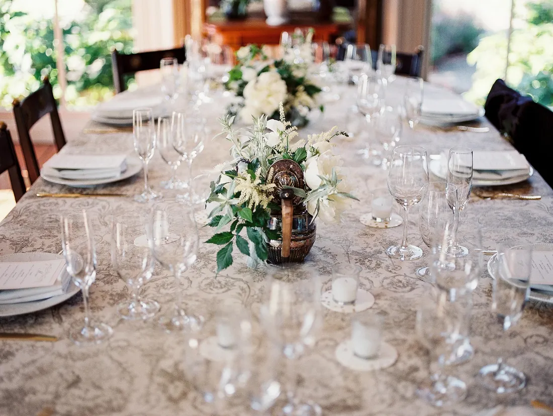 Film photograph of a long reception table with glassware and white flowers