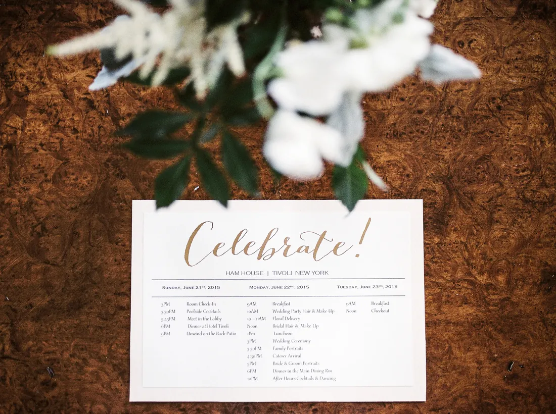 Film photograph of a wedding weekend schedule card under white flowers