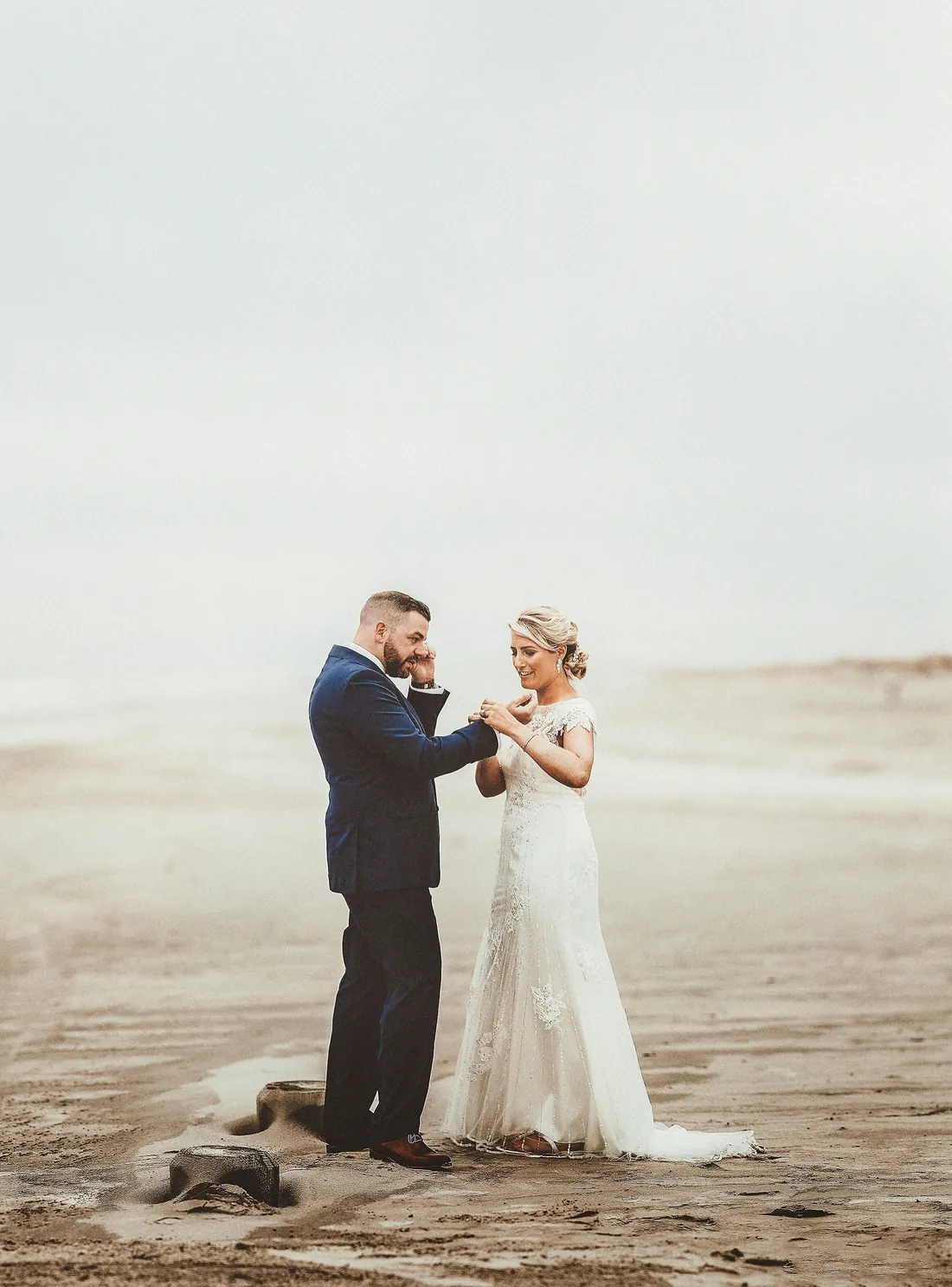 Bride and groom sharing an emotional moment on a misty beach