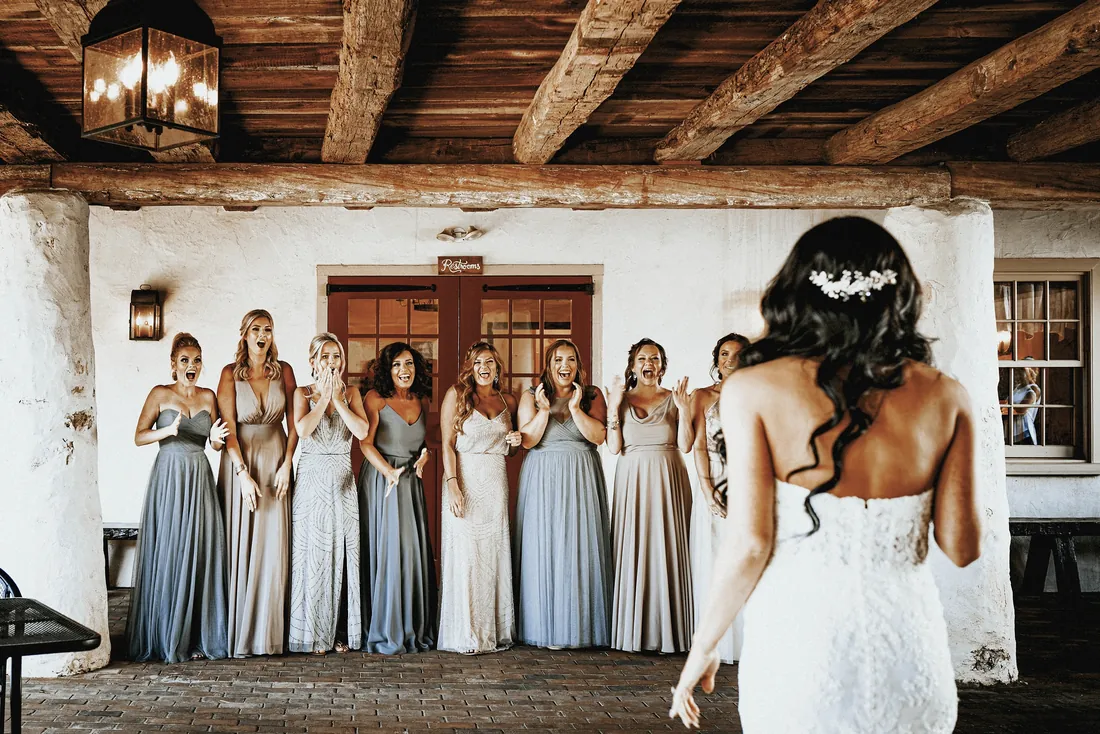 Bridesmaids reacting as the bride walks toward them