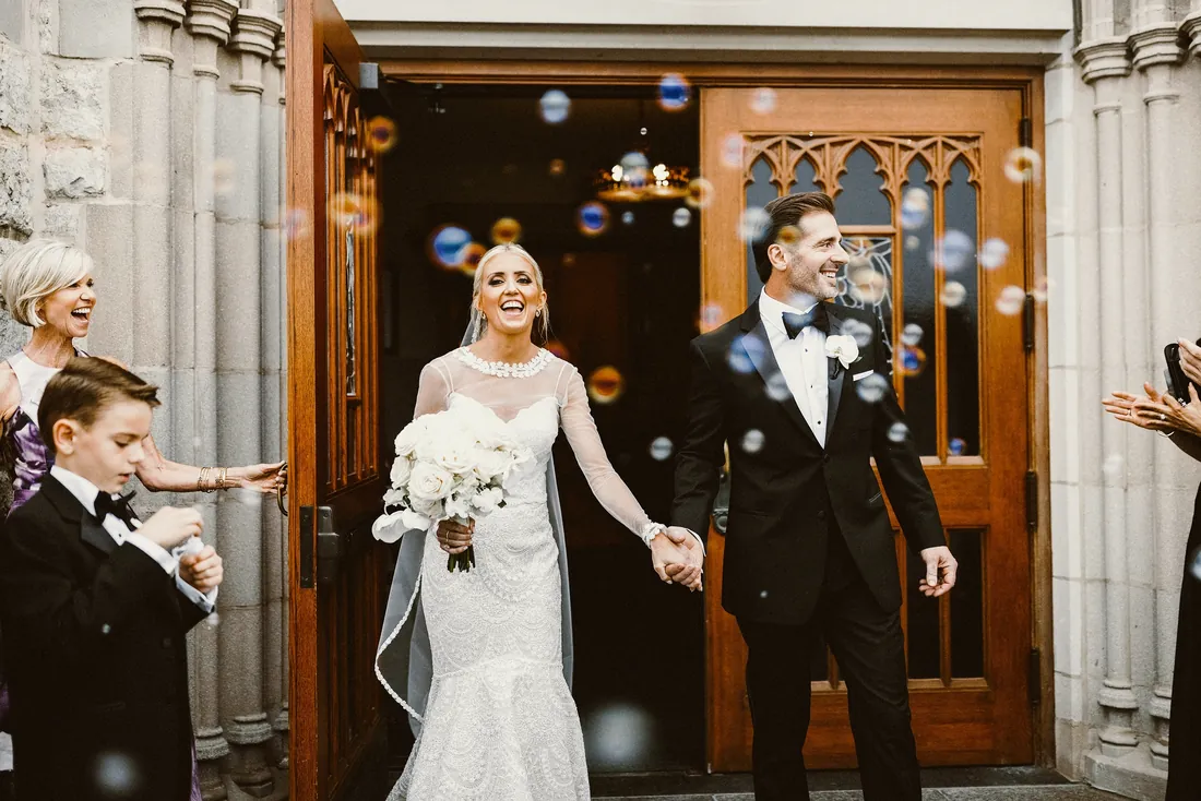 Bride and groom walking out of the church through bubbles