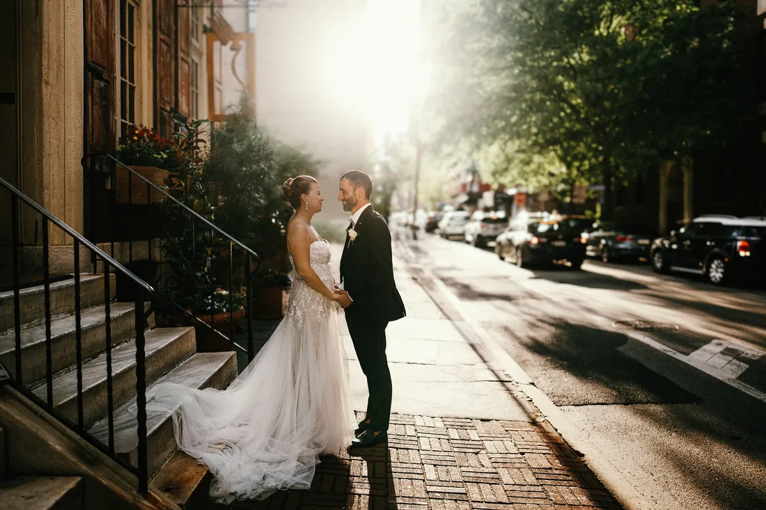 Bride and groom on a city sidewalk in golden afternoon light