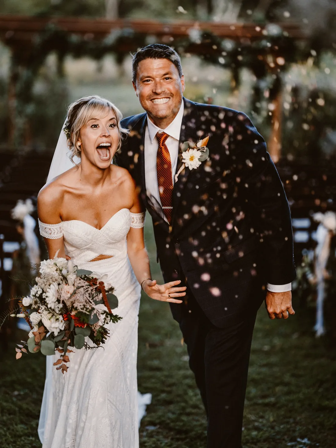Bride and groom laughing as confetti falls after the ceremony