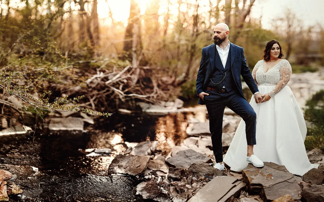 Bride and groom by a rocky creek at sunset