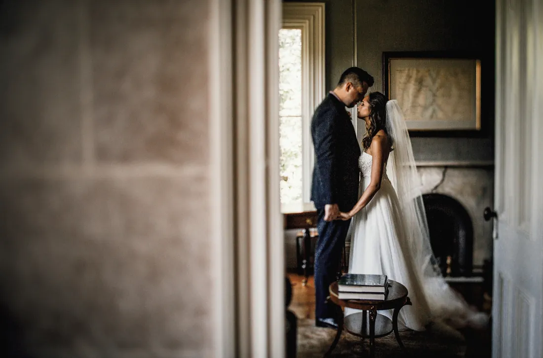 Bride and groom by a fireplace seen through a doorway