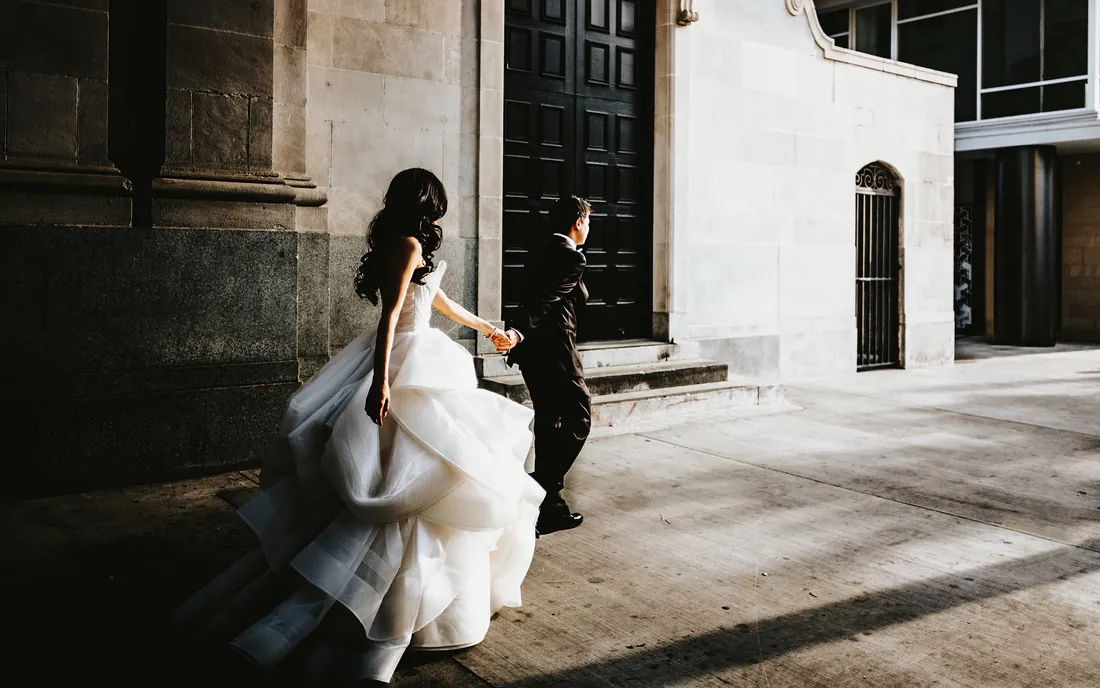 Bride and groom walking toward a stone building