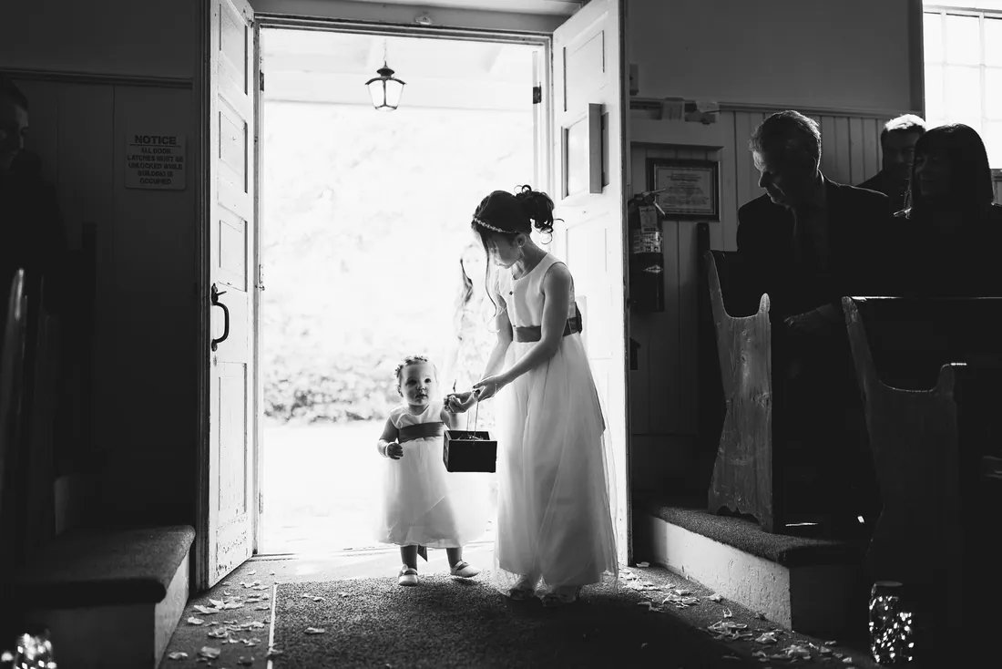 Black and white photo of a flower girl walking in at the church door