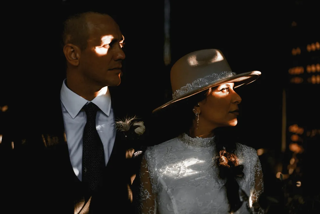 Groom and his bride in a wide-brimmed hat in dramatic light