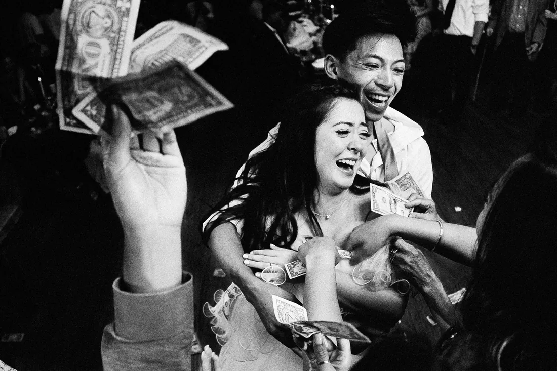 Black and white photo of a bride laughing during the money dance