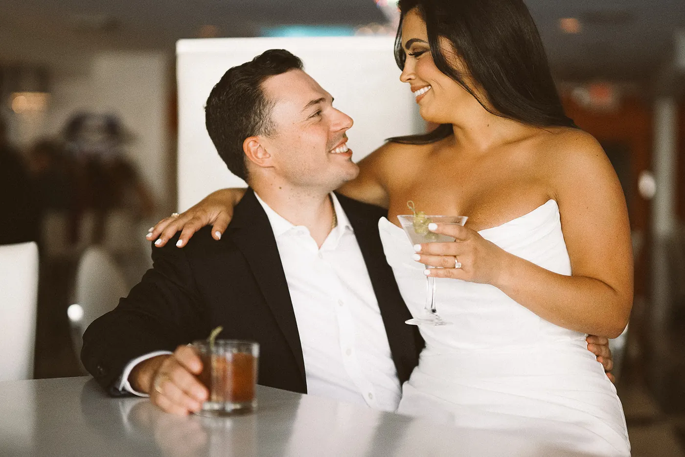 Celeste with her arm around Branon as they laugh over drinks