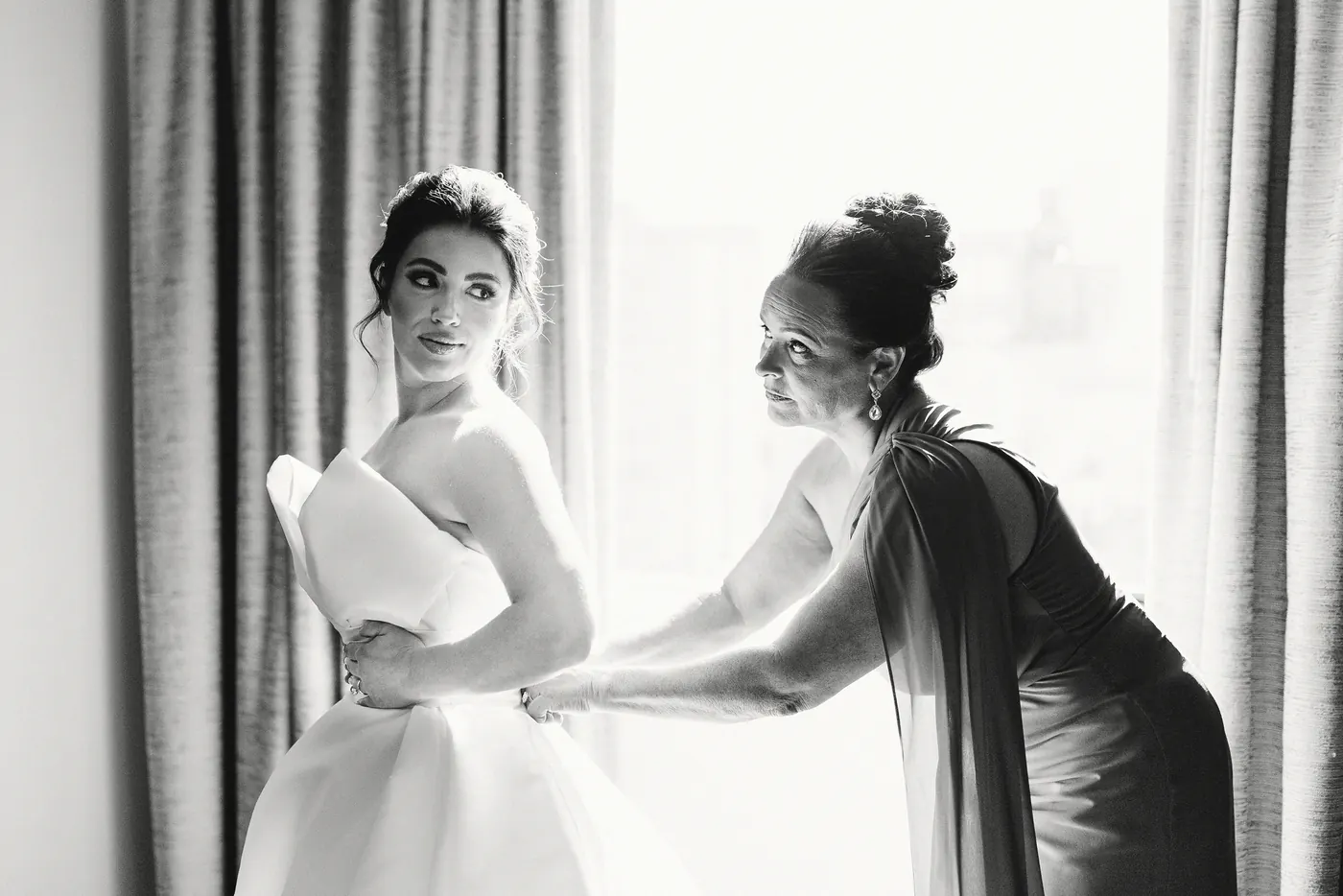 Black and white photo of Celeste's mom helping her into her wedding dress