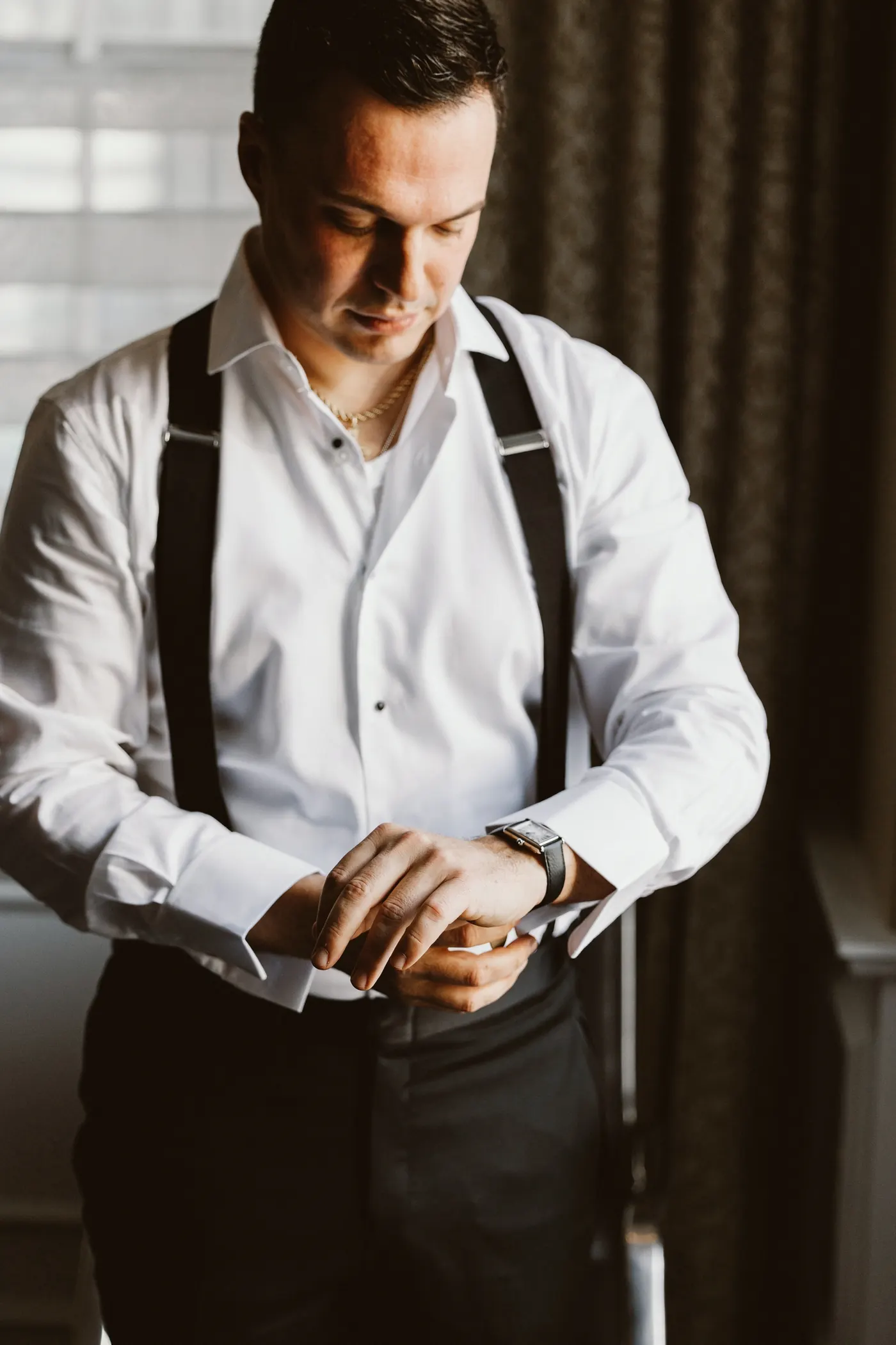 Branon putting on his watch by the window