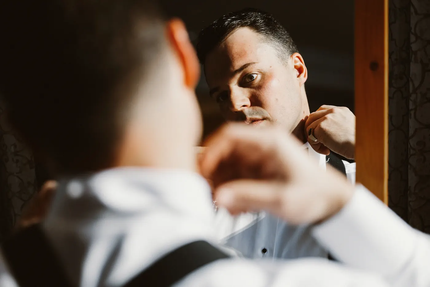 Branon adjusting his bow tie in the mirror