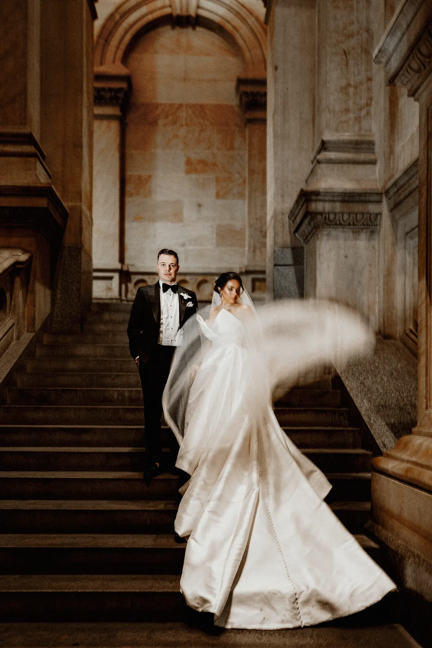 Celeste's veil swirling as they walk down the stone stairs at Philadelphia City Hall