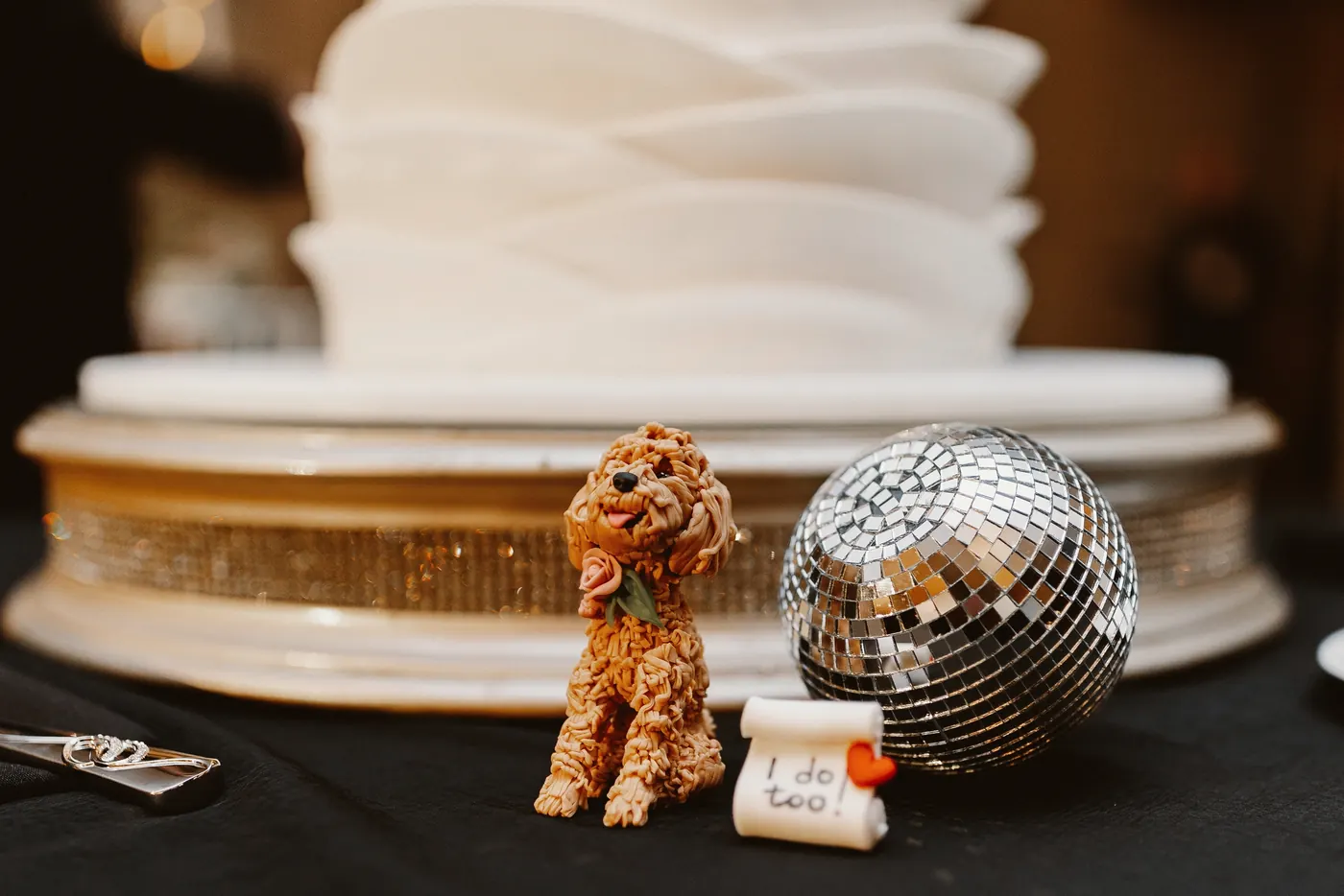 A disco ball and a little dog figure beside the wedding cake at The Vie by Cescaphe in Philadelphia