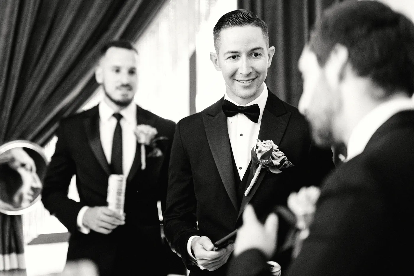 Black and white photo of Chris with his groomsmen as his boutonniere is pinned