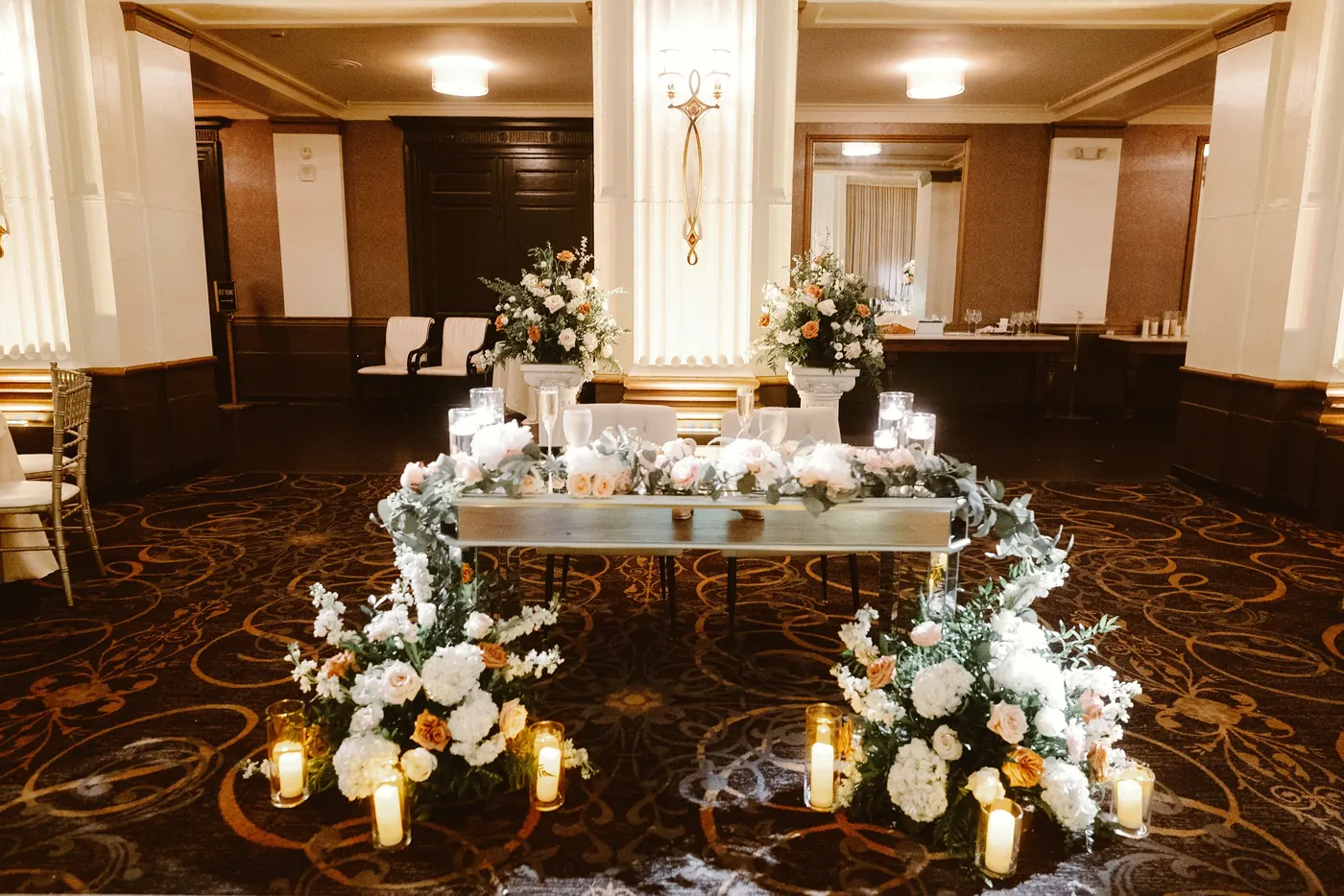 The sweetheart table surrounded by white flowers and candles at Cescaphe Ballroom at the Ben in Philadelphia
