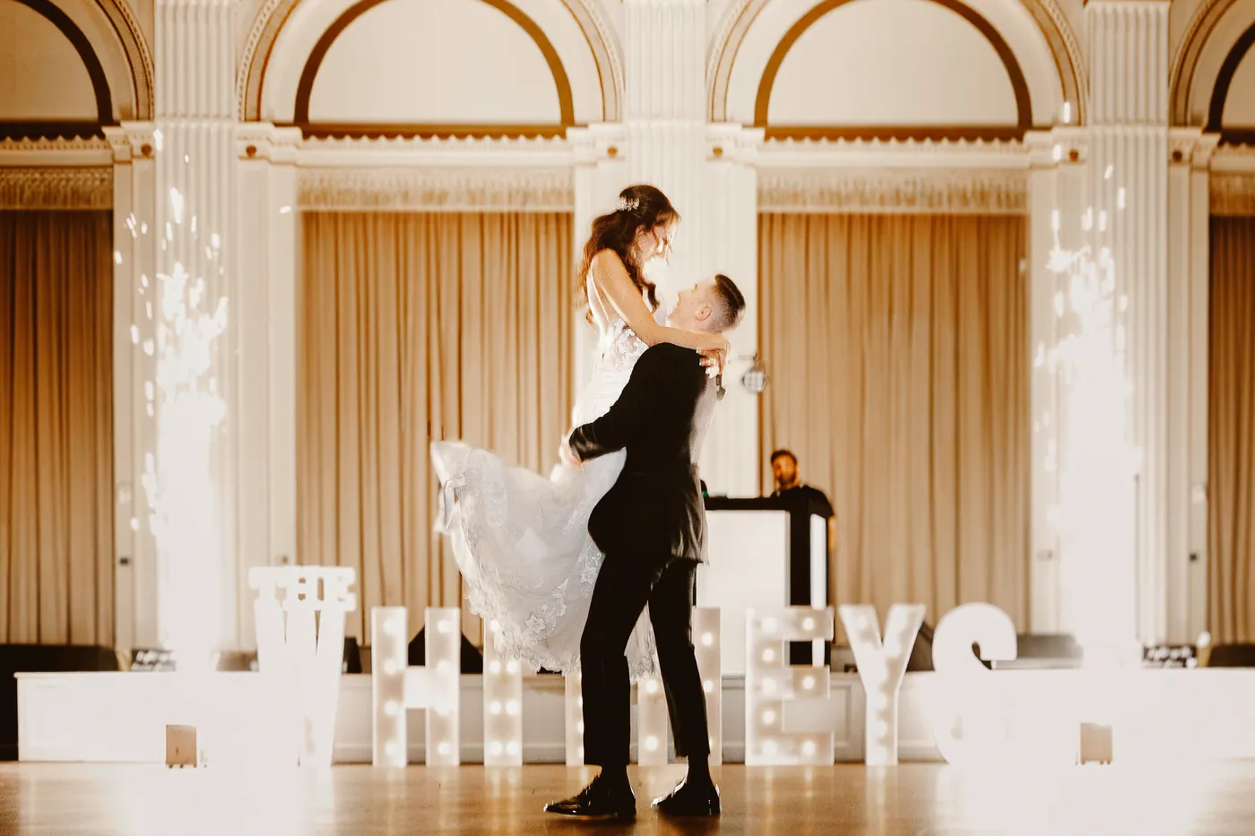 Chris lifting Danielle as cold sparks go off behind them at Cescaphe Ballroom at the Ben in Philadelphia