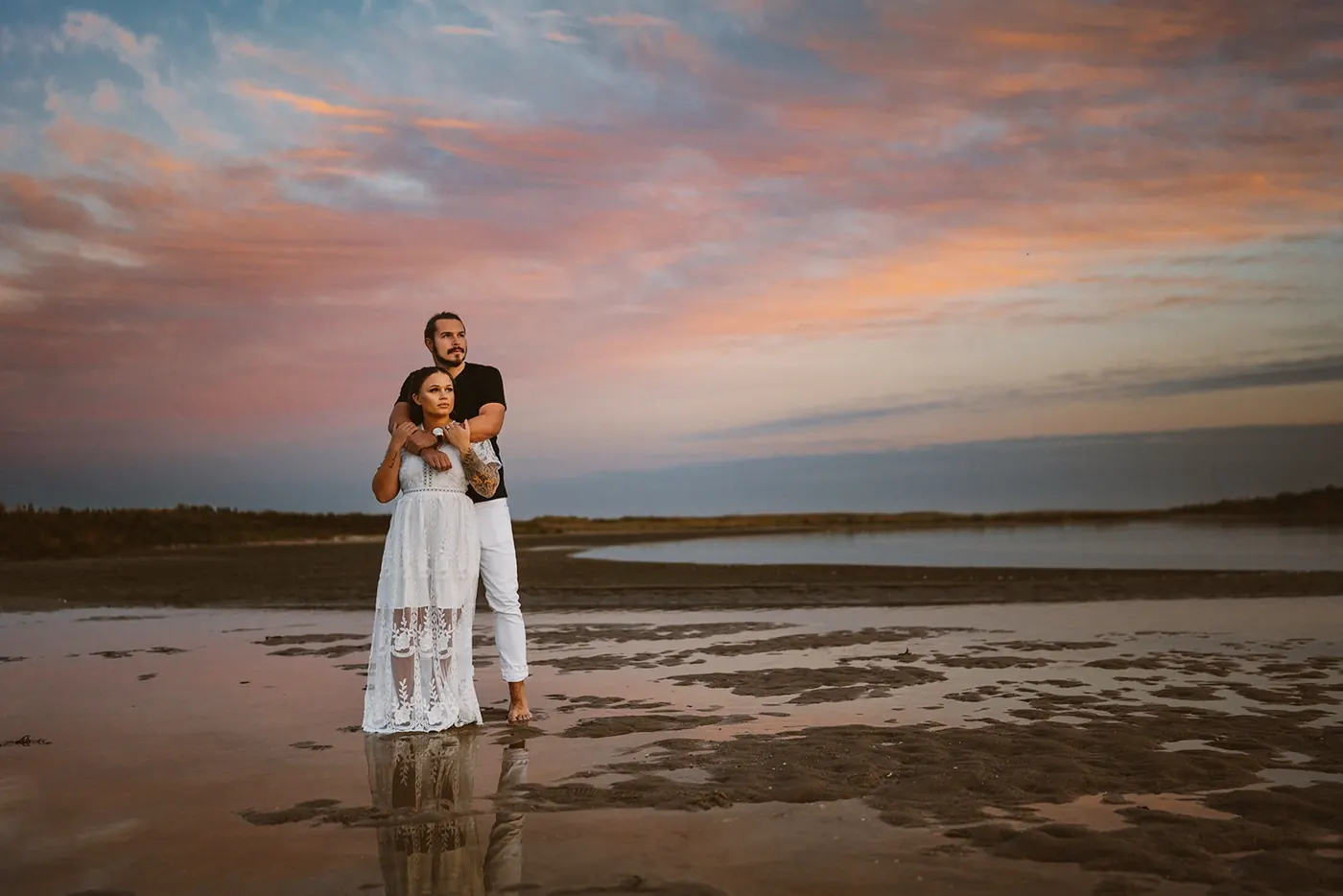 Dan and Madison standing in shallow water under a pink and blue sky near Barnegat Lighthouse on Long Beach Island, NJ