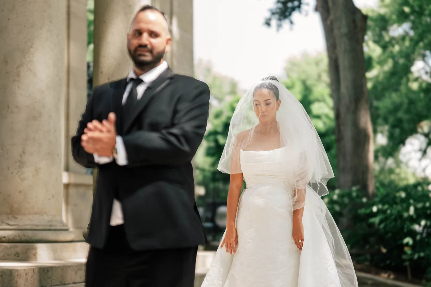 Simon waiting with his back turned as Gianna walks up behind him for their first look