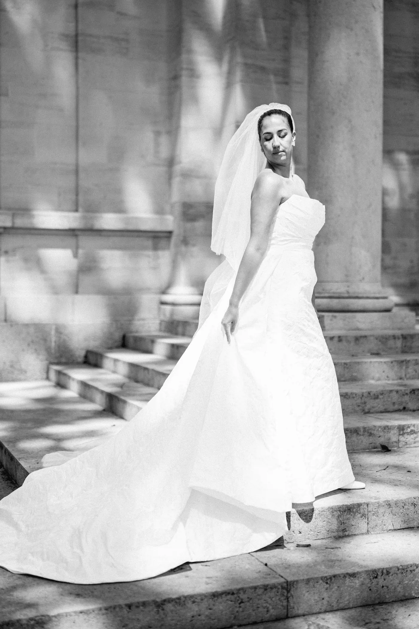 Black and white photo of Gianna on the stone steps with her train sweeping behind her