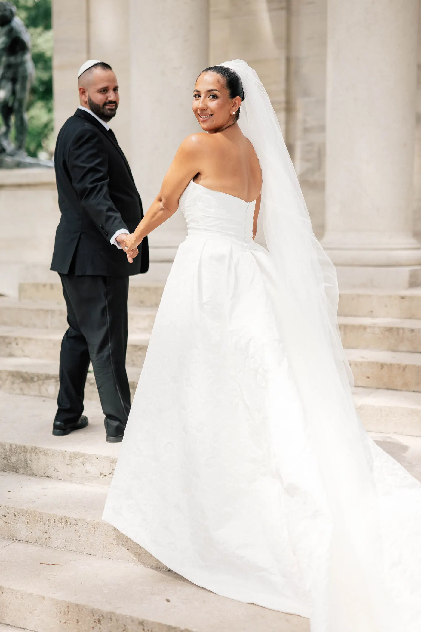 Gianna looking back as she leads Simon up the steps of the Rodin Museum