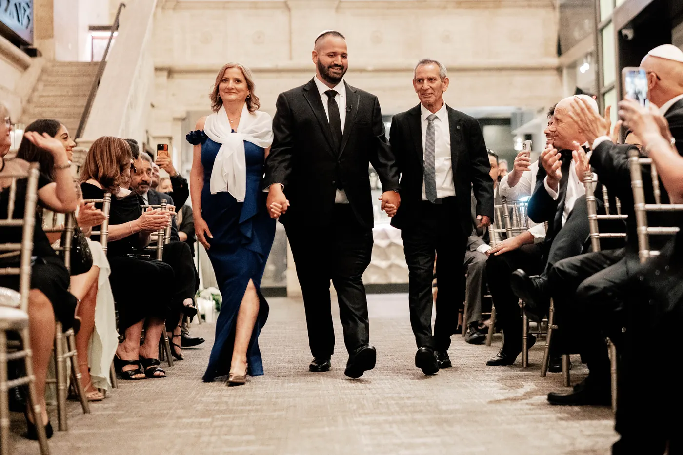 Simon walking down the aisle with his parents at the Union Trust
