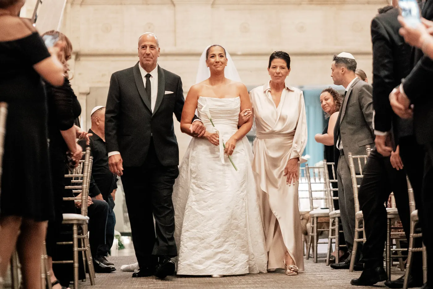 Gianna's parents walking her down the aisle in the grand hall of the Union Trust