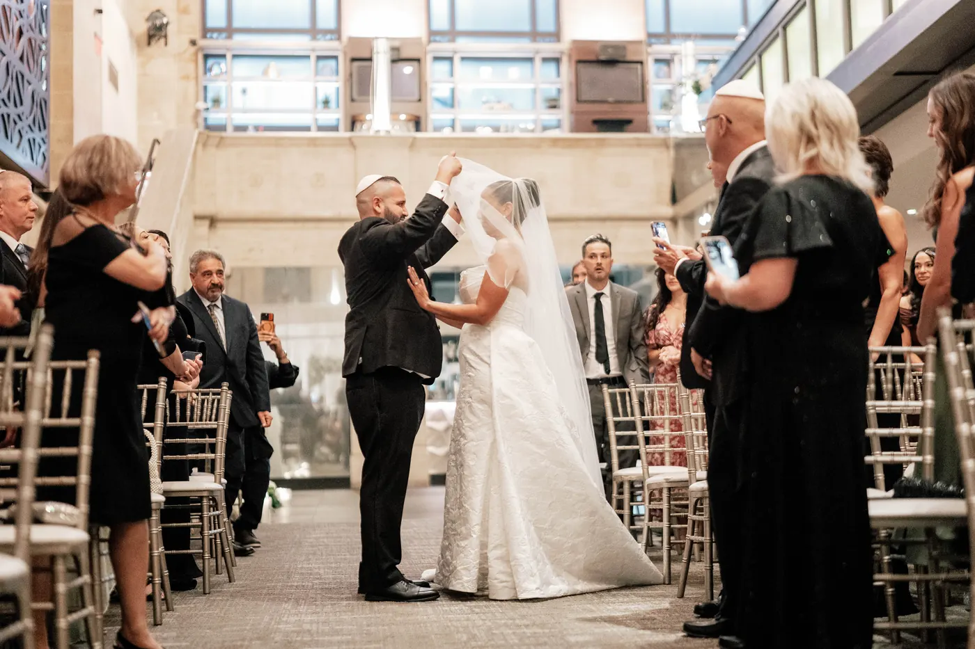 Simon lifting Gianna's veil as she reaches him in the aisle