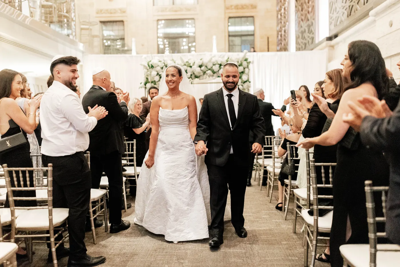 Guests cheering as Gianna and Simon walk back up the aisle