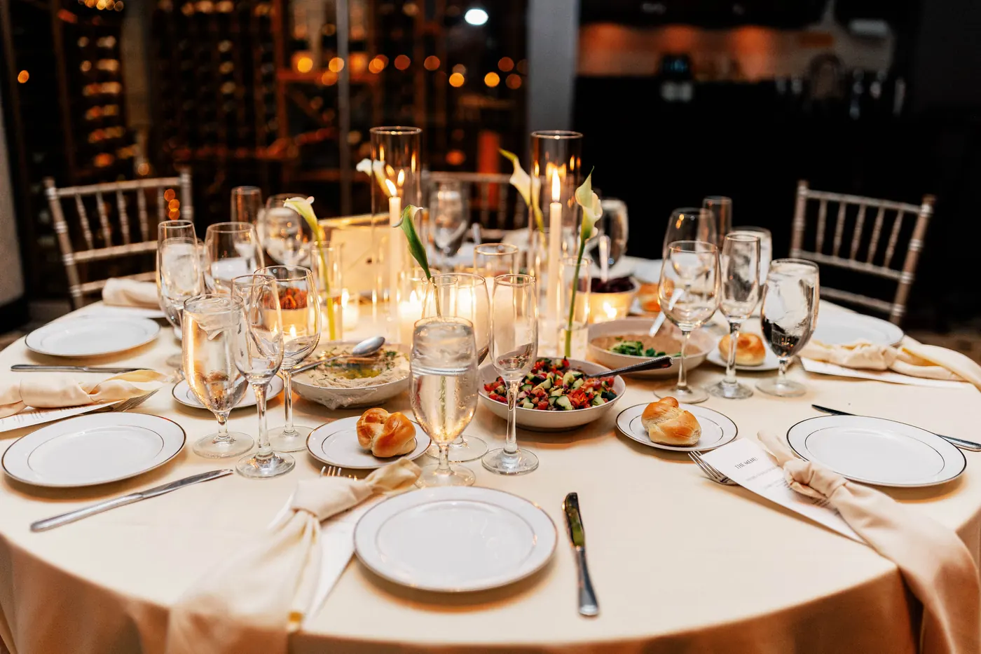 Candlelit reception table with challah rolls, salads and calla lilies