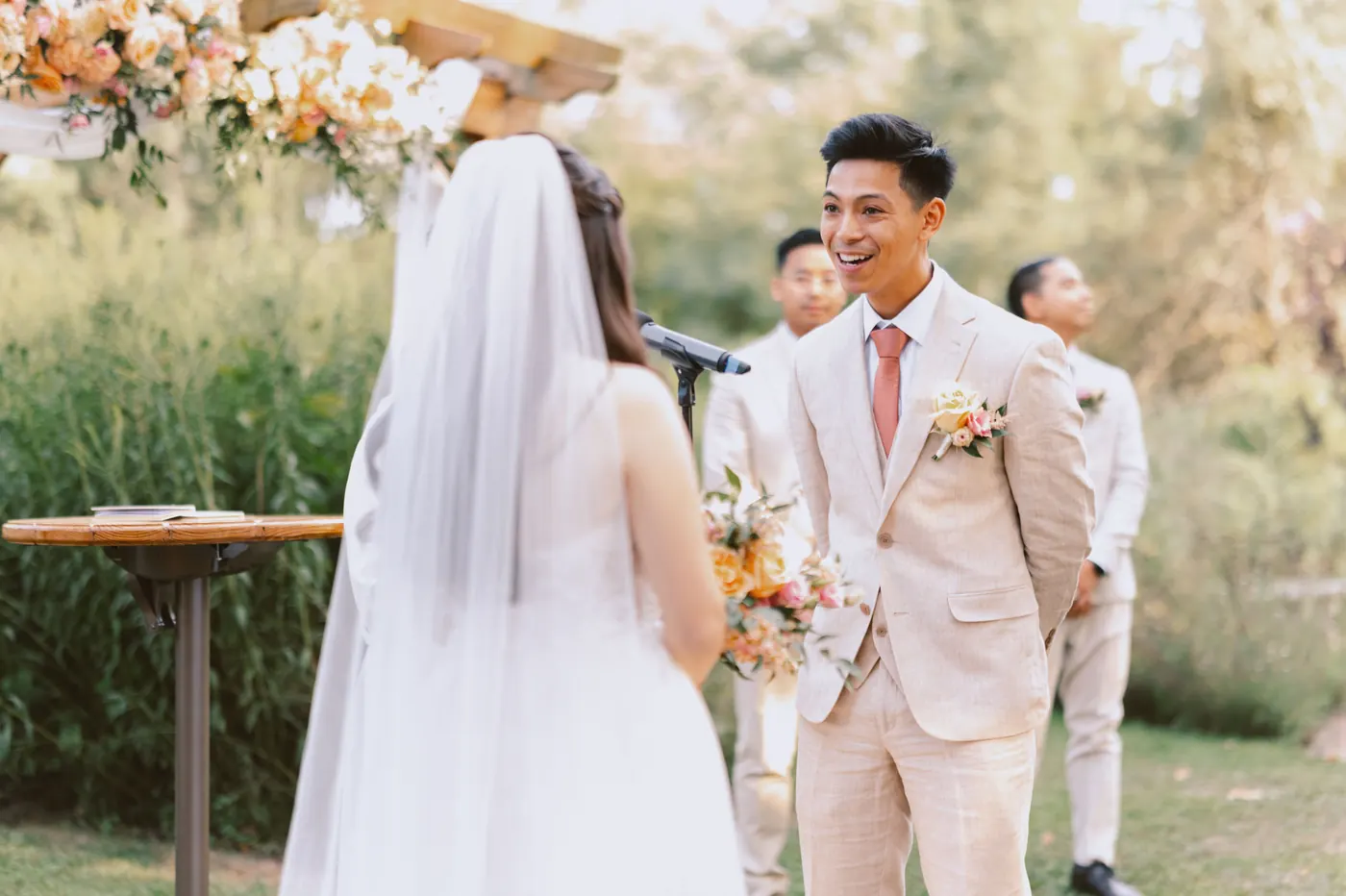 Ivan smiling as Camille reaches him at the flower-covered pergola