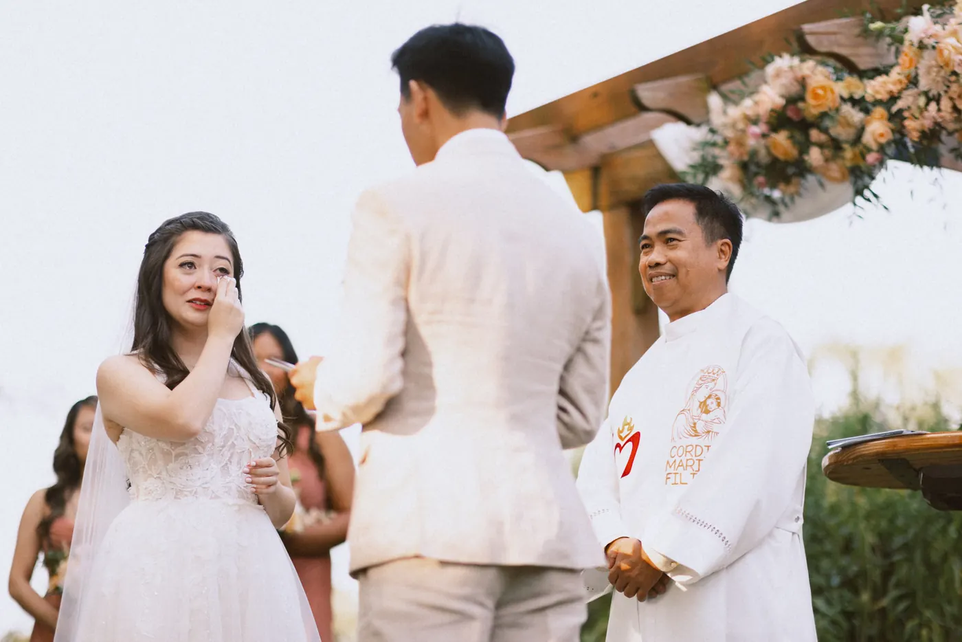 Camille tearing up during the vows as the priest smiles