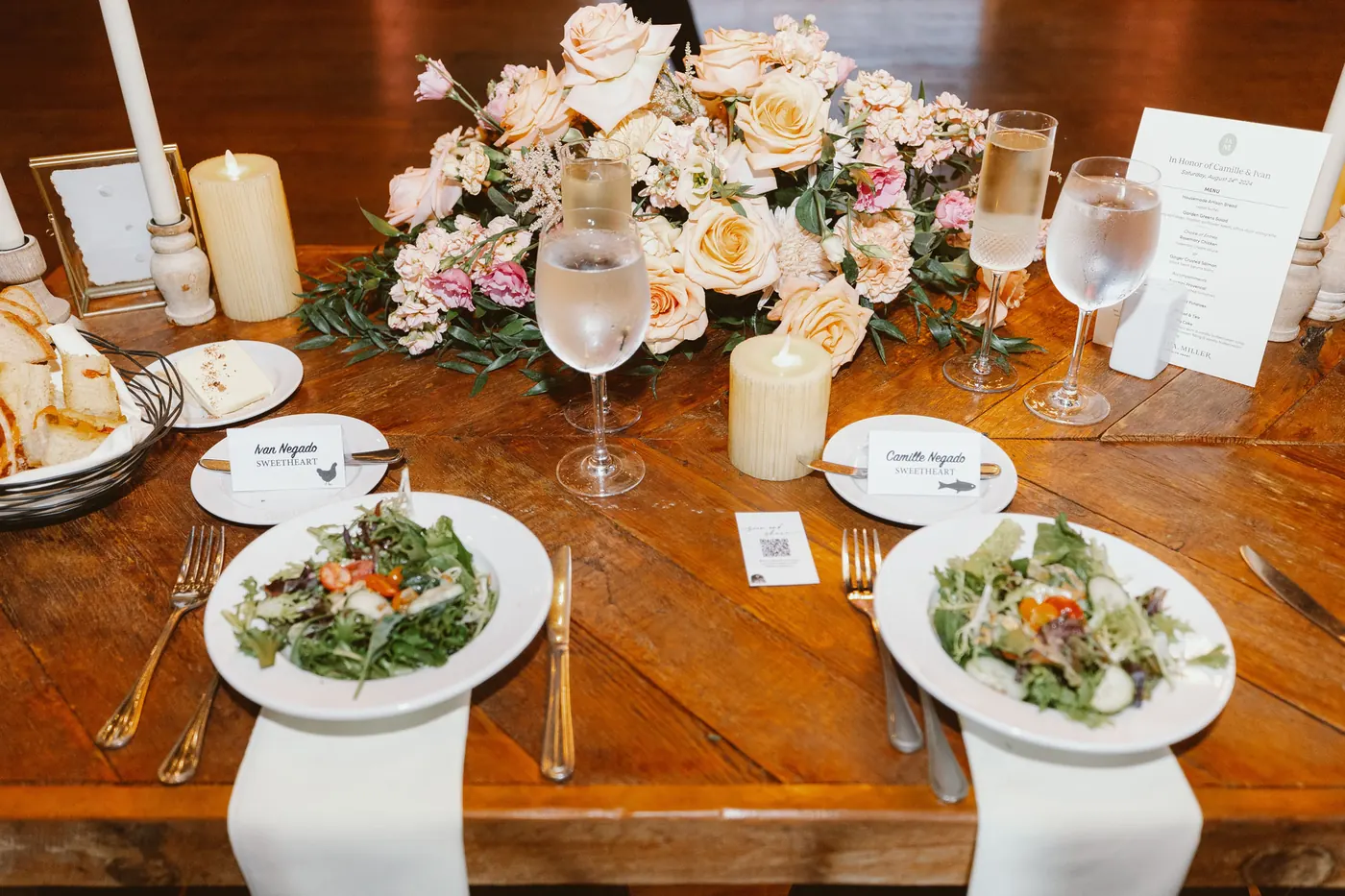 Reception table set with salads, candles and peach roses in the barn