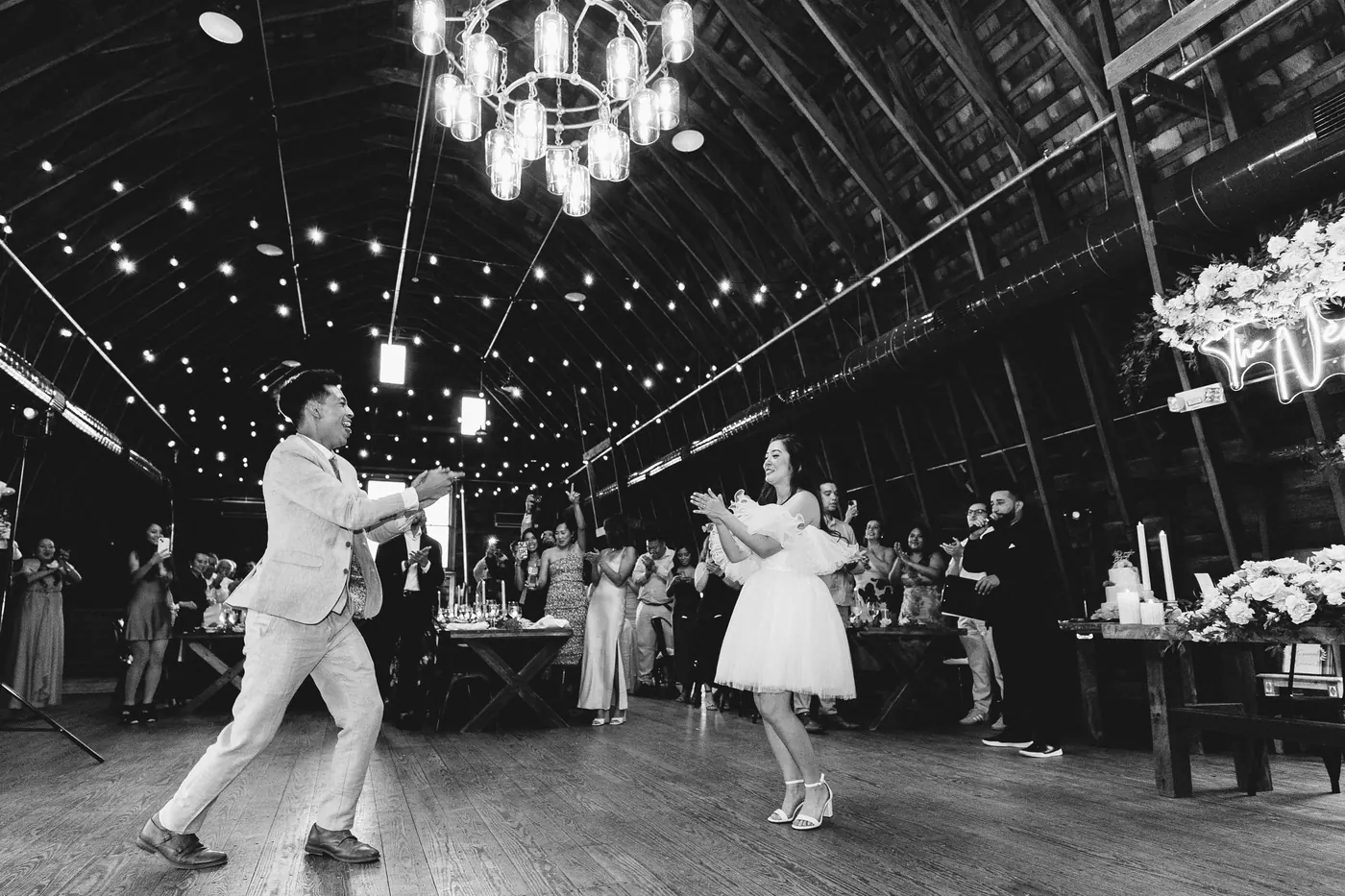 Black and white photo of Ivan and Camille dancing under the barn chandelier