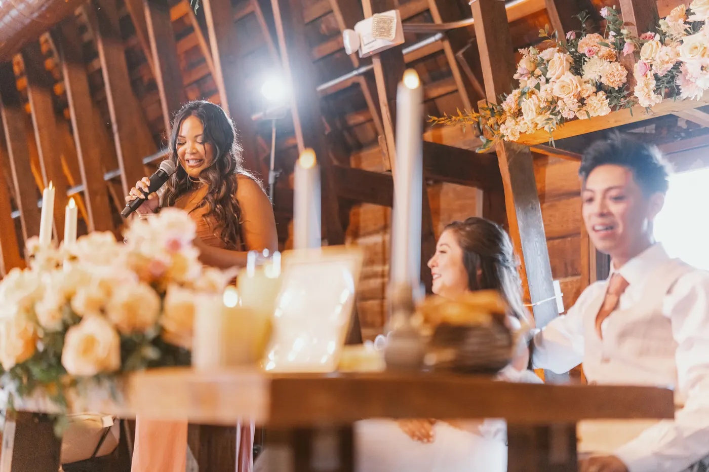 A bridesmaid giving a toast as Camille and Ivan listen at the sweetheart table