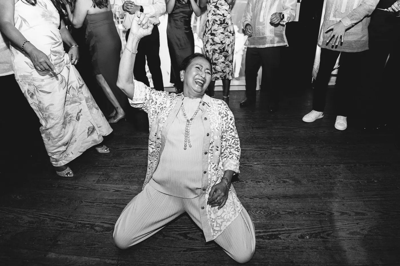 Black and white photo of a guest dancing on her knees on the dance floor