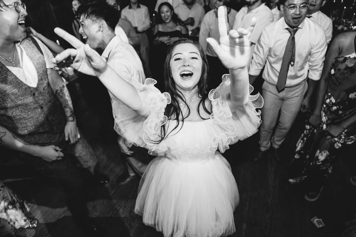 Black and white photo of Camille dancing with her arms out on the packed dance floor