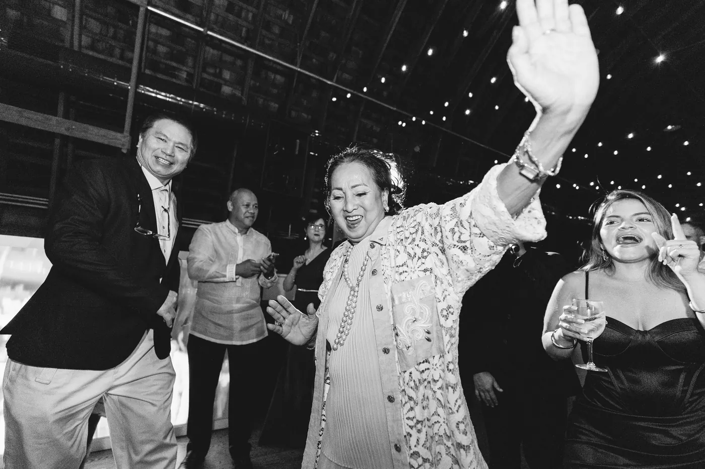 Black and white photo of guests dancing under the string lights
