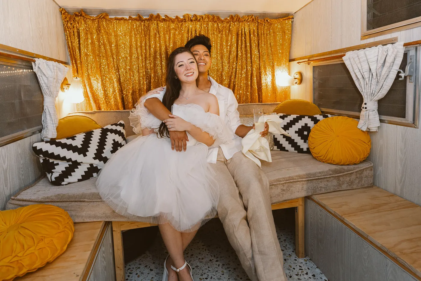 Camille and Ivan sitting together inside a vintage camper at Bishop Farmstead