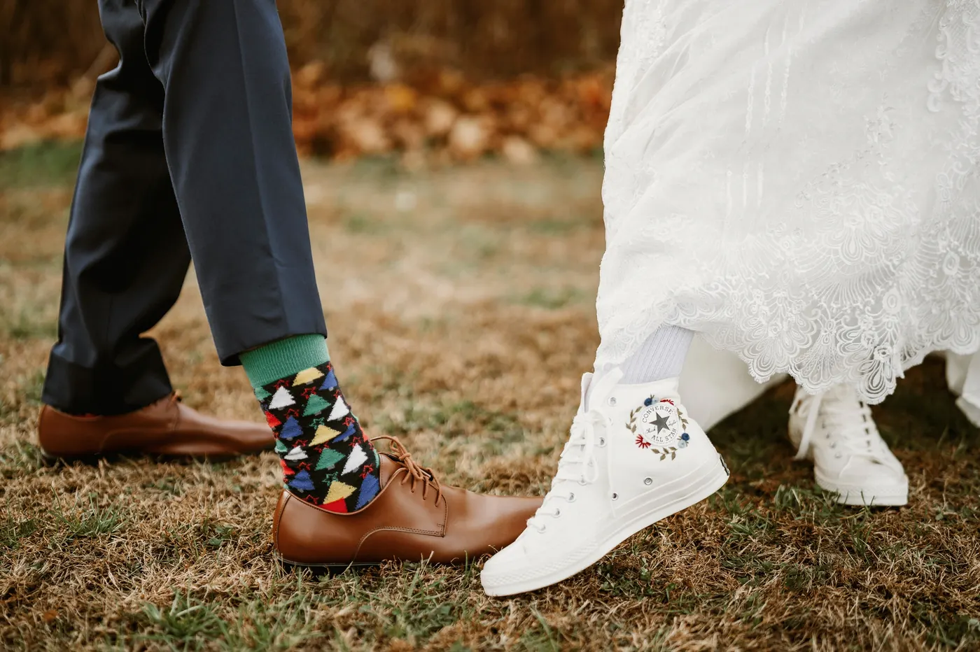 Close-up of Jimmy's colorful socks and brown shoes beside Kelsey's embroidered white sneakers